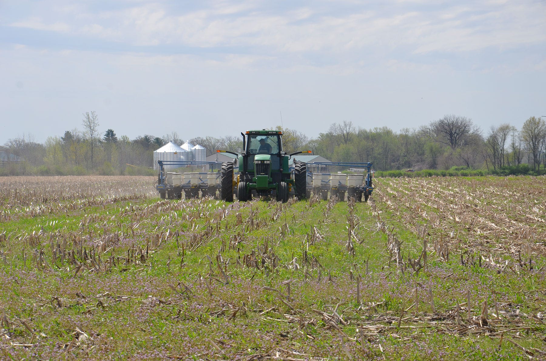 A tractor planting into a no-till cornfield
