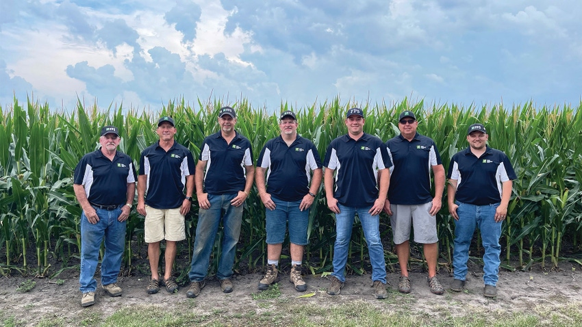 group of men standing in front of a cornfield