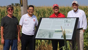 4 men standing around informative sign about Knorr-Holden corn research plot