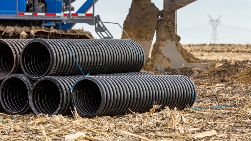 Black corrugated water drainage pipe on a farm field
