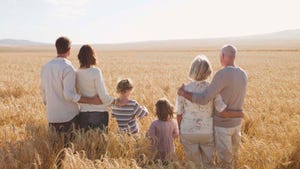 Family of farmers standing in wheat field looking toward the horizon, symbolizing planning for the future of the farm.