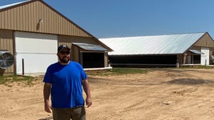 man stands by chicken barns