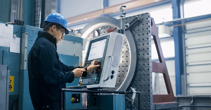 Factory worker is programming a CNC milling machine with a tablet computer. Factory worker is programming a CNC milling machine with a tablet computer.
