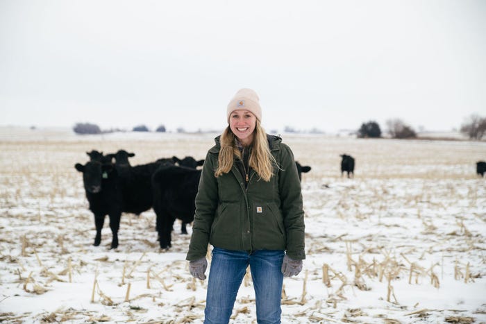 Hannah standing by angus cattle in pasture in the winter