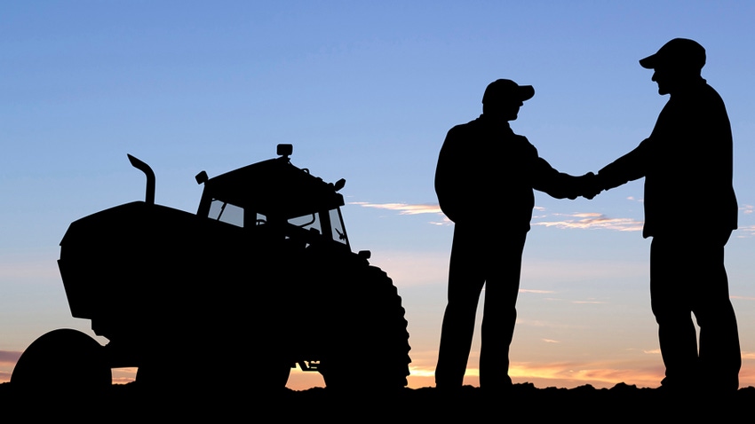 Farmers shaking hands with tractor in background