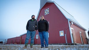 Matt and Liz Hulsizer stand in front of red barn