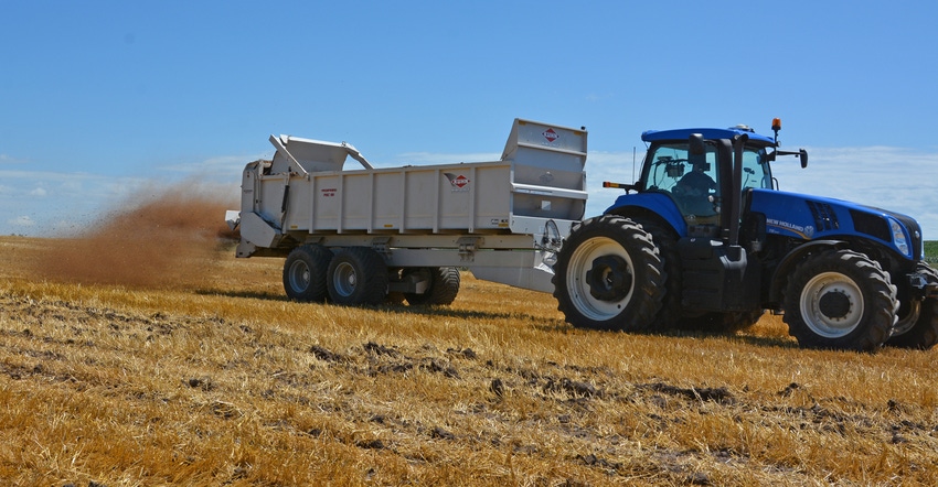 tractor and cart hauling and spreading manure across field