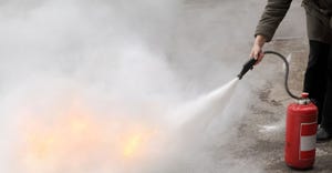 Up close fire fighter spraying flames with fire extinguisher
