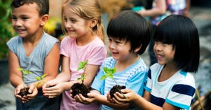 school children holding plants in hands