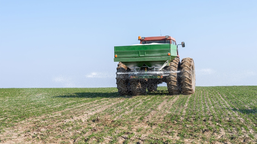 A tractor spraying fertilizer on a field