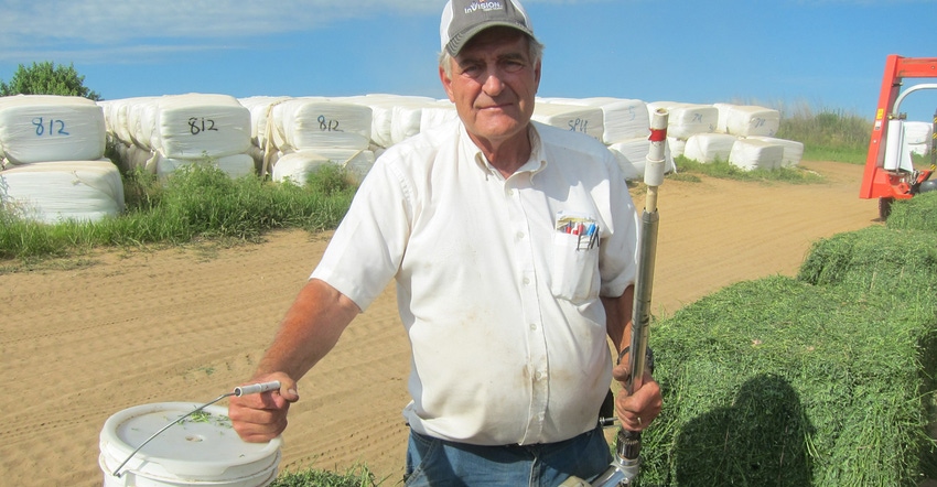 Kendall Guither of Walnut, Ill., holding bucket with bales of hay in background