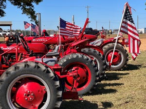 antique tractors in a row, flying American flags