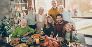  Photo of big family standing hugging behind feast table
