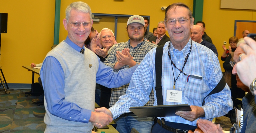 Jim Mintert presents Howard Doster with a plaque at the Top Farmer workshop