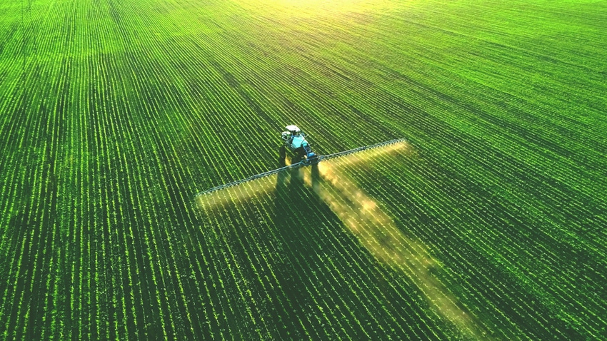 aerial shot of a tractor and sprayer in a field