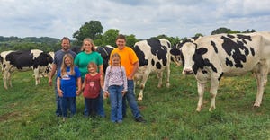 David and Katy Lammers and their children Dawson, Lilly, Hope and Cora stand among Holstein cows in their pasture