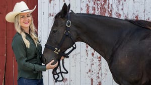 Sarah Jordan standing with brown horse in front of red and white barn