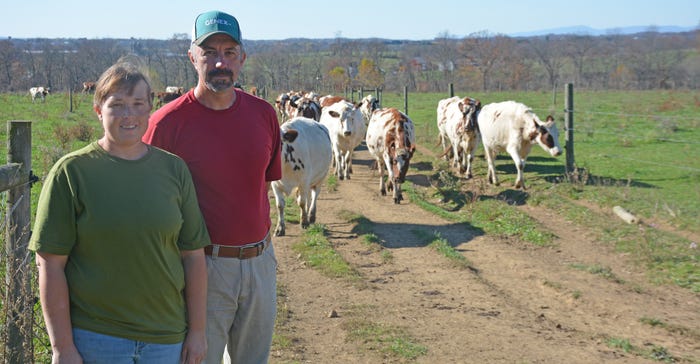 Roy and Jen Coale standing in front of a herd of cattle out in the pasture
