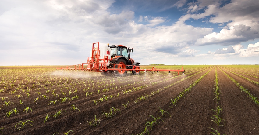 Tractor spraying pesticides on corn field with sprayer Tractor spraying pesticides on corn field with sprayer