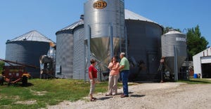 two women and a mand talk infront of a grain bin
