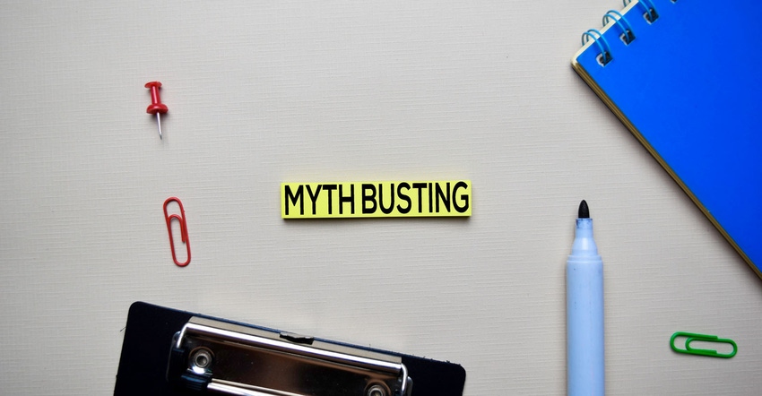 Post-it notes reads 'myth busting' with pen and notebook adjacent
