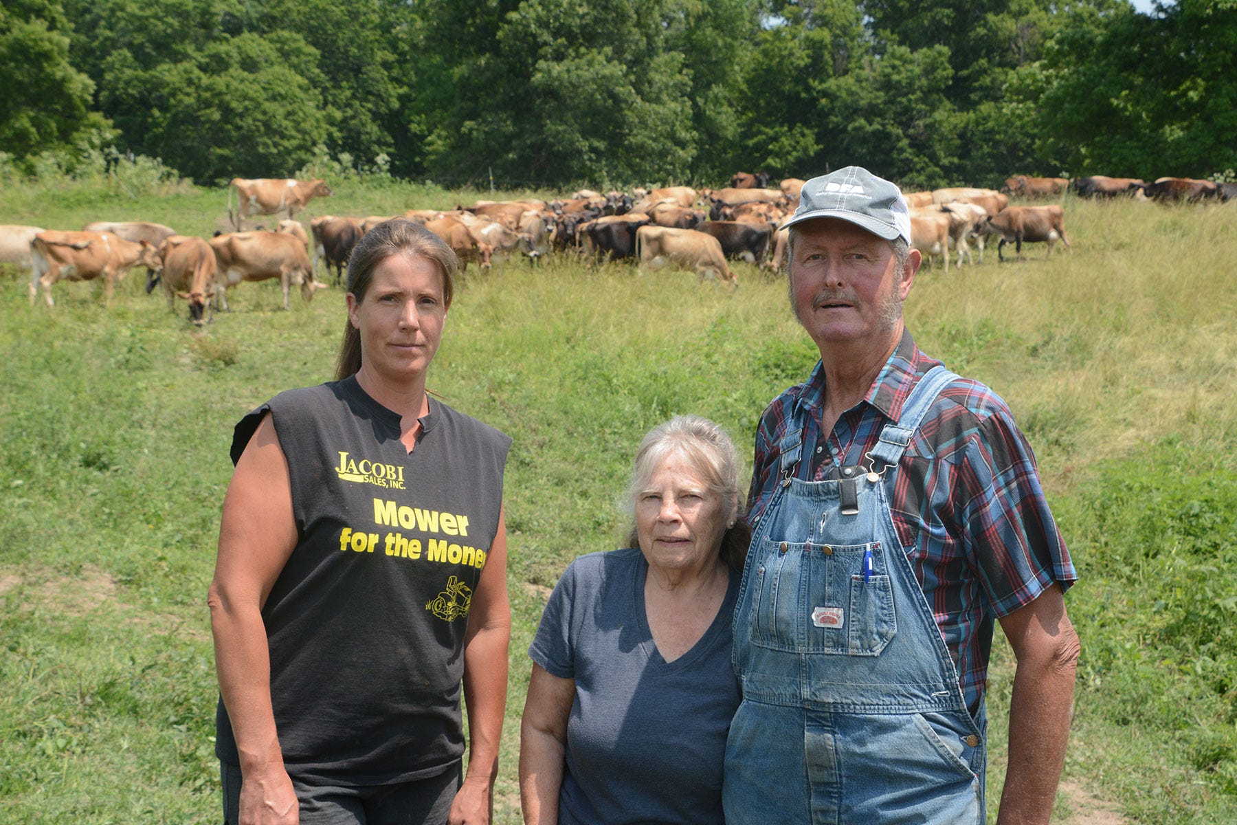 Sarah, Judy and Mike Ponsford stand in a pasture with a herd of Jersey cows behind them Sarah, Judy and Mike Ponsford stand in a pasture with a herd of Jersey cows behind them