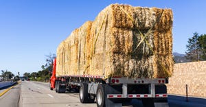 Truck transporting bales of hay on freeway