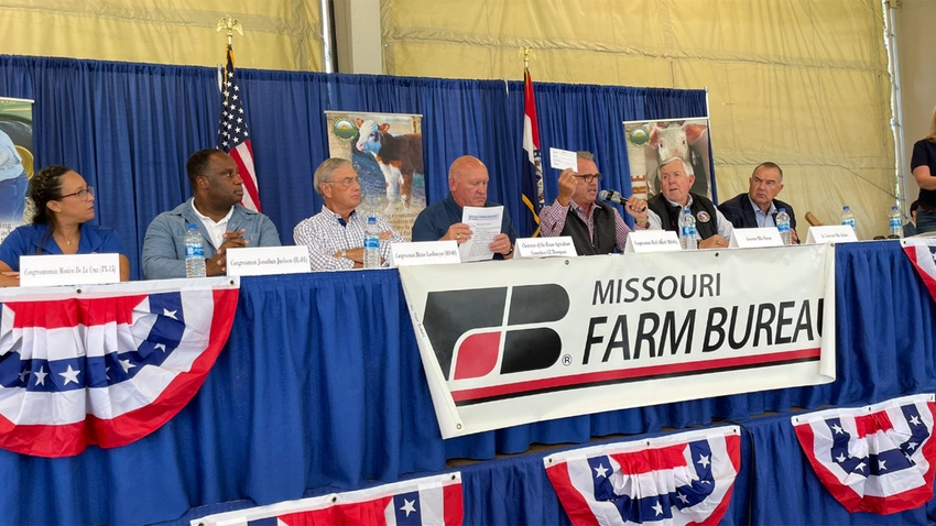 People on a panel sitting at a blue table with patriotic decorations and Missouri Farm Bureau sign.