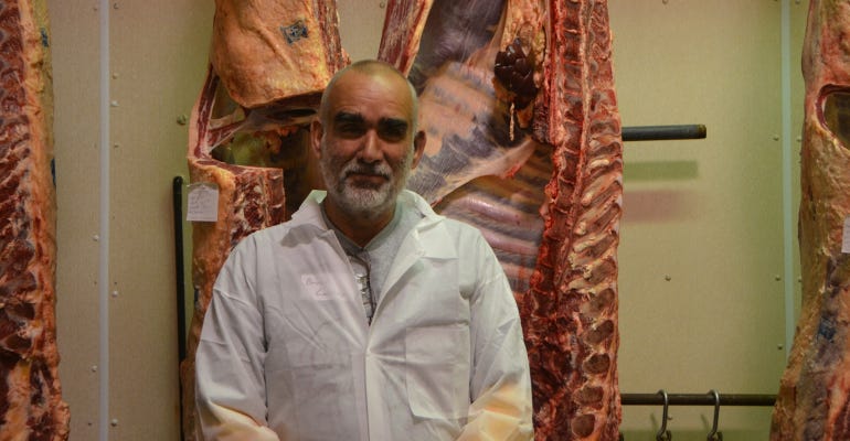 Cattle producer Bruce Carney poses in front of his grass-fed beef carcasses 