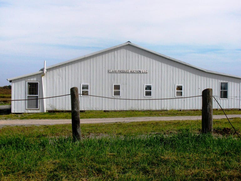 A white building with a roped fence with wooden posts in front