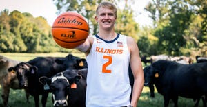 Conner Serven in his Fighting Illini jersey holding a basketball towards the camera