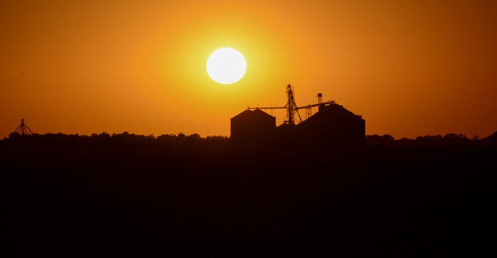 An orange sunset behind grain bins