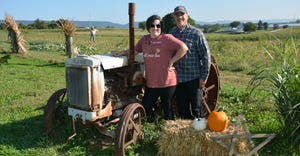 Patrick and Kristy Mitchell stand in front of antique tractor on their pumpkin farm, Patchwork Pumpkin Patch