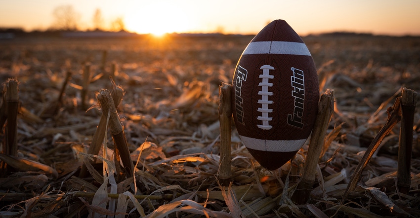 Franklin football propped up in corn residue as sun sets in background