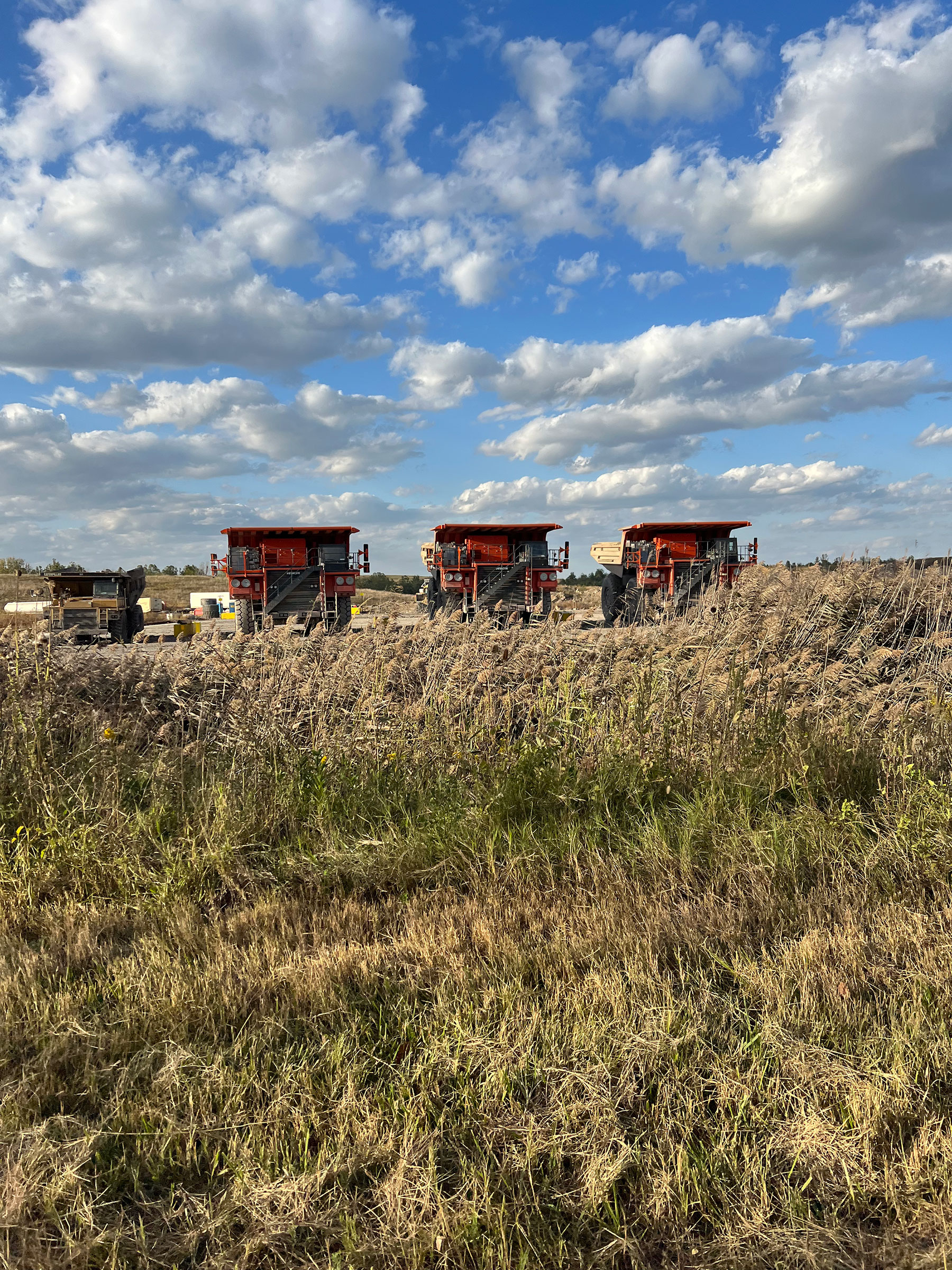 3 large dump trucks near a mine