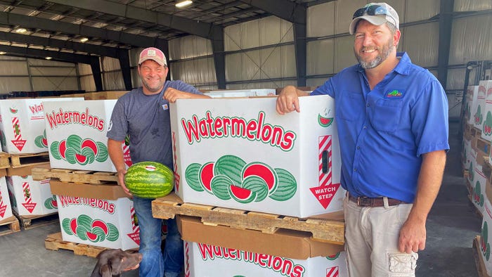 Brooks and Brandon Cardinal pose next to pallets of watermelon.