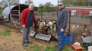 Rusty Plummer and Michael Metzger stand in front of goat pen