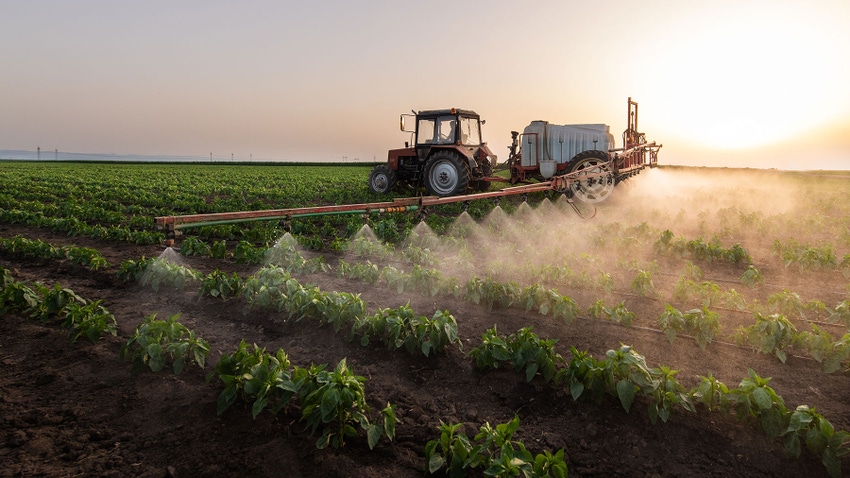 Tractor spraying pesticides on crops