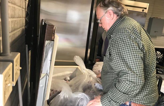 Jim Droege stocks the freezer at God's Storehouse