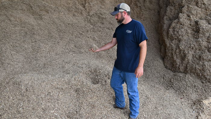 A man standing in a large pile of mulch