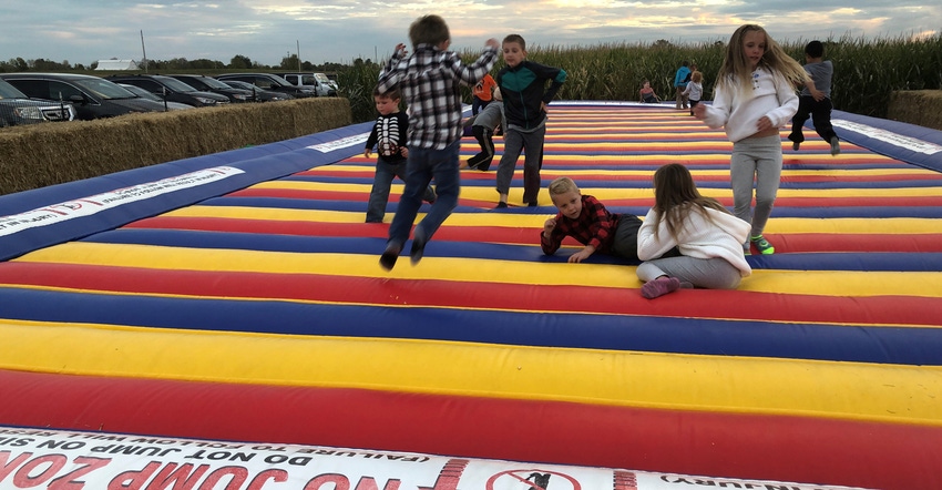 children jumping on inflatable pad on farm