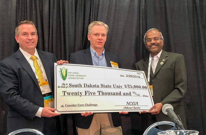 Jim Bauman and Bruce Peterson present South Dakota State University Distinguished Professor Kasiviswanathan Muthukumarappan with a check to support his research