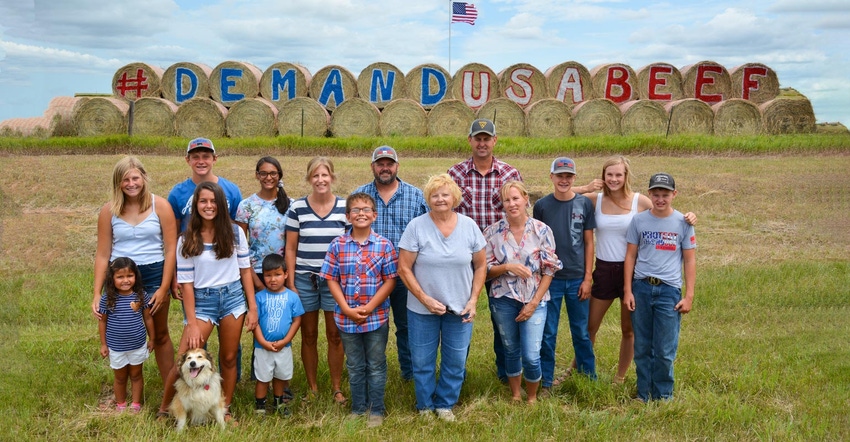 A family of agriculture advocates standing in front of a massive pile of hay bale with the words demand U.S. beef and an Amer
