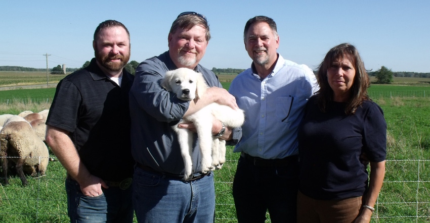 Greg Babcock holding dog, Freedom Belle, awarded to him through Operation Farm Dog. He is standing with 2 men and a woman 