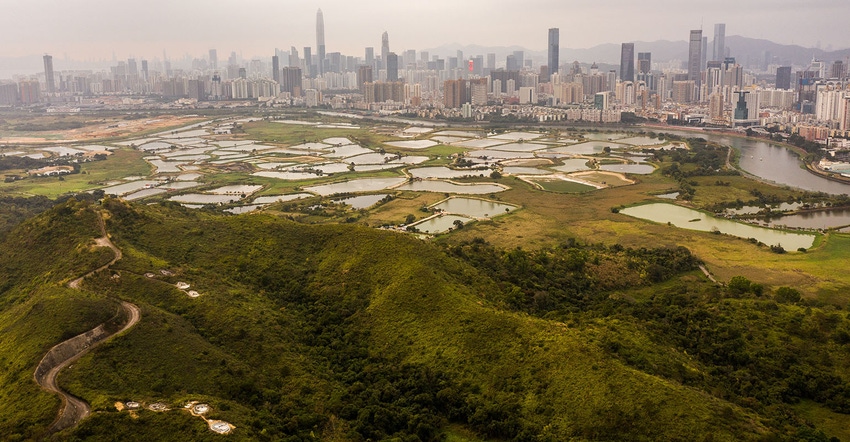 This aerial photo shows farmland and fisheries on Hong Kong's border, with the skyline of the Chinese city of Shenzhen in the This aerial photo shows farmland and fisheries on Hong Kong's border, with the skyline of the Chinese city of Shenzhen in the