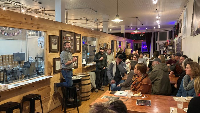 Standing speaker at brewpub with audience at tables