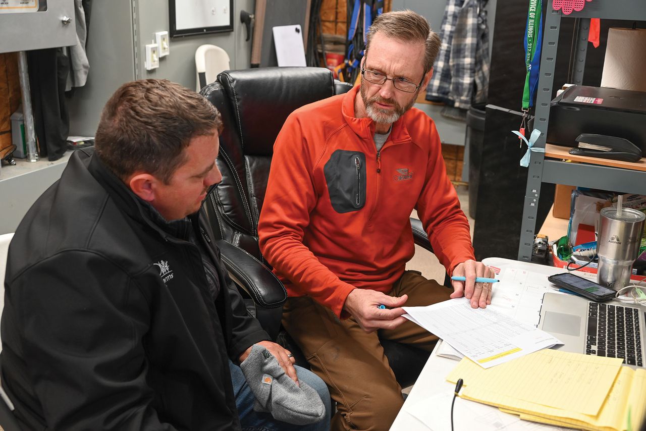 farmers Aaron Gingerich and Jeff Brown sit at a desk in discussion