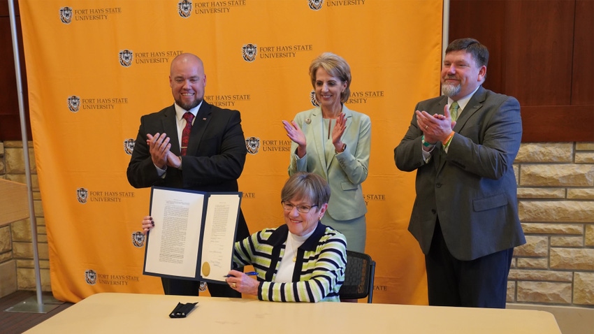 Kansas Gov. Laura Kelly holds a house bill, joined by college presidents