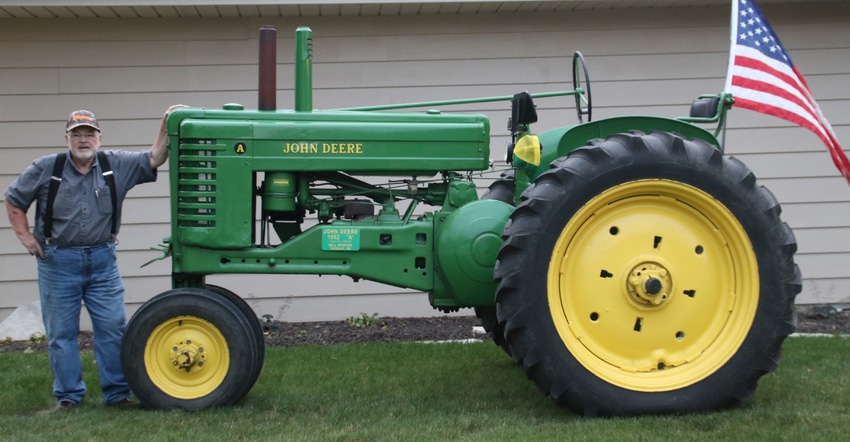 Bill Pfister standing with his 1952 John Deere A tractor