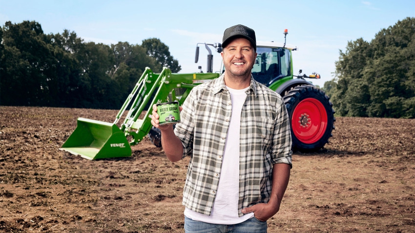 Country music star Luke Bryan holds a can of peanuts while posing in a field in front of a tractor